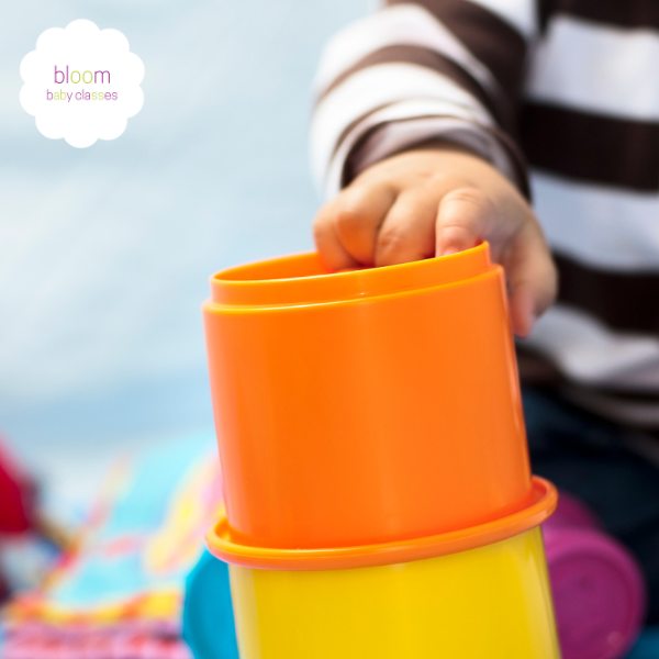 baby using hand and eye coordination stacking cups
